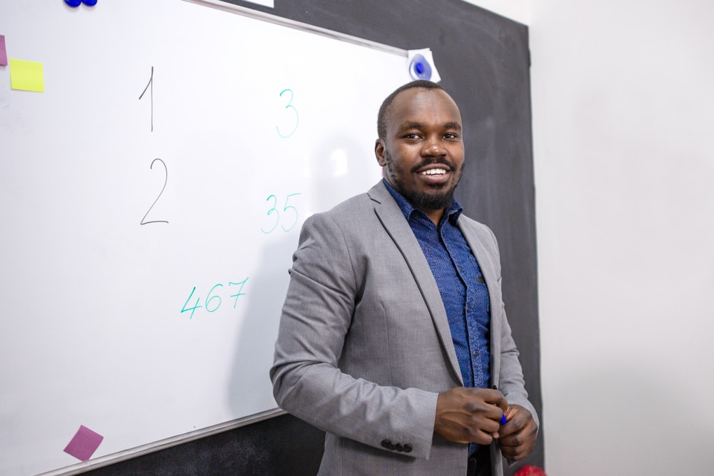 African,School,Teacher,Standing,At,The,Blackboard,In,The,Classroom