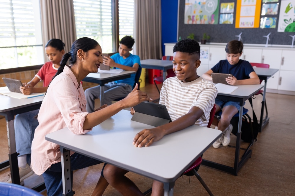 Indian,Female,Teacher,Helping,Student,With,Tablet,In,Classroom,,Other