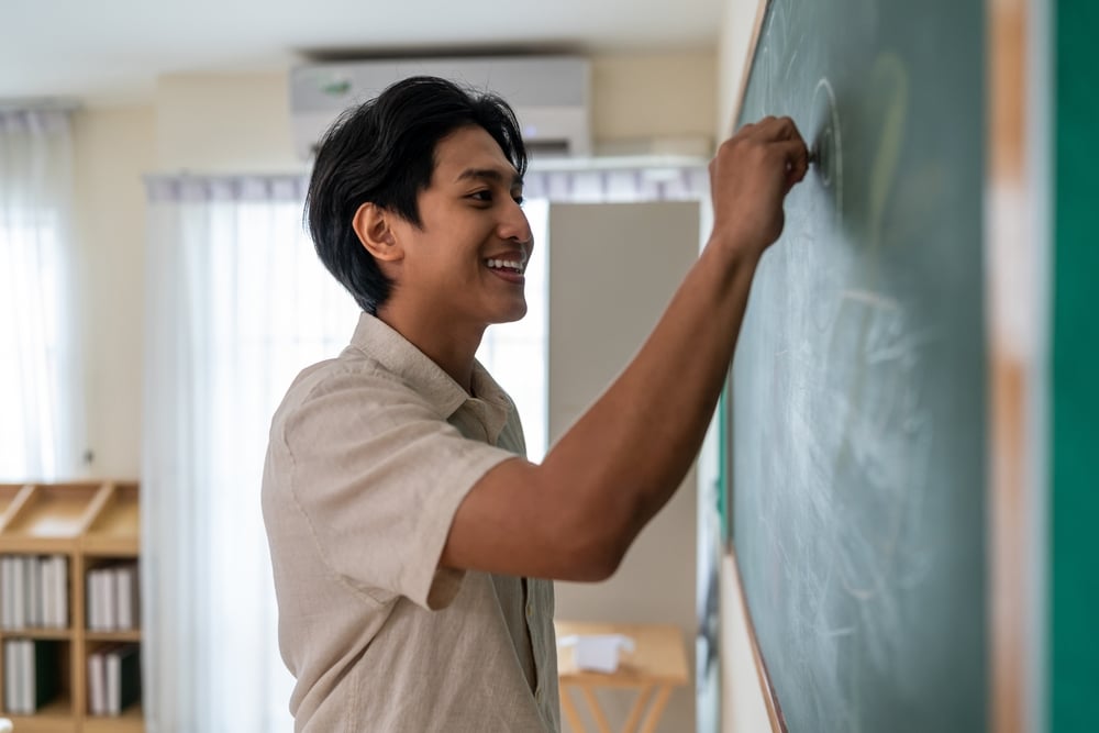 Asian,Male,Teacher,Use,White,Chalk,Write,On,Blackboard,To