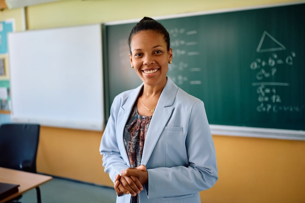 Happy,African,American,Female,Teacher,In,The,Classroom,Looking,At
